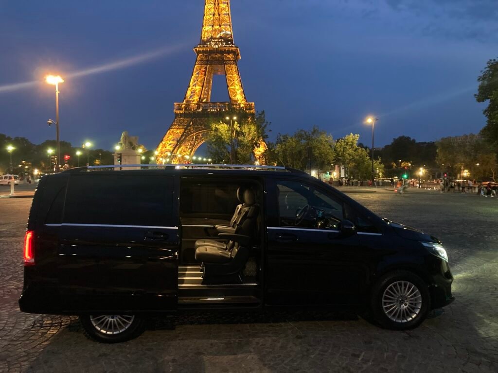 Van VTC Mercedes Classe V, porte latérale ouverte, devant la tour Eiffel au crépuscule